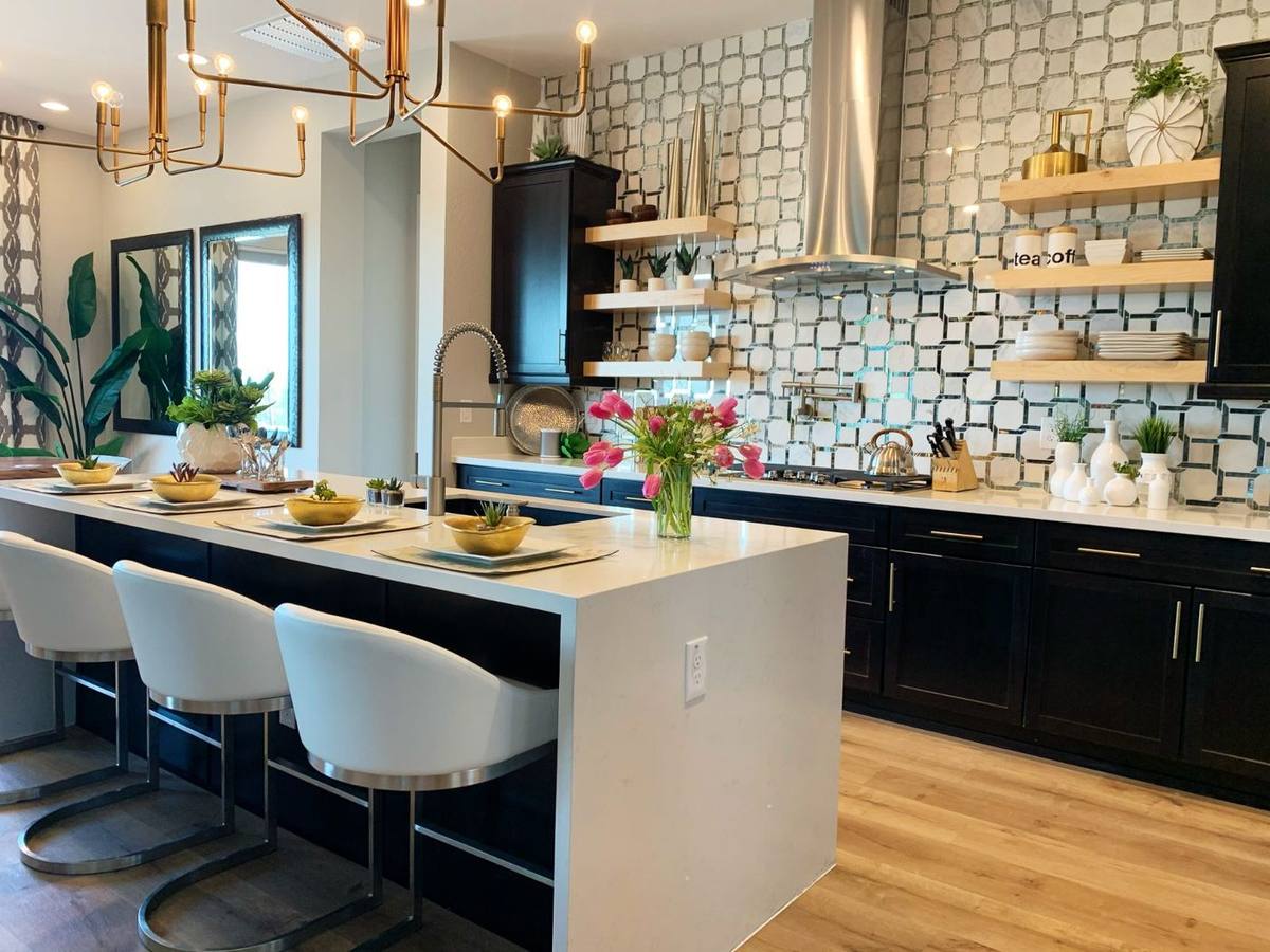 Modern luxury kitchen featuring a white quartz waterfall island, dark cabinetry, and geometric tile backsplash