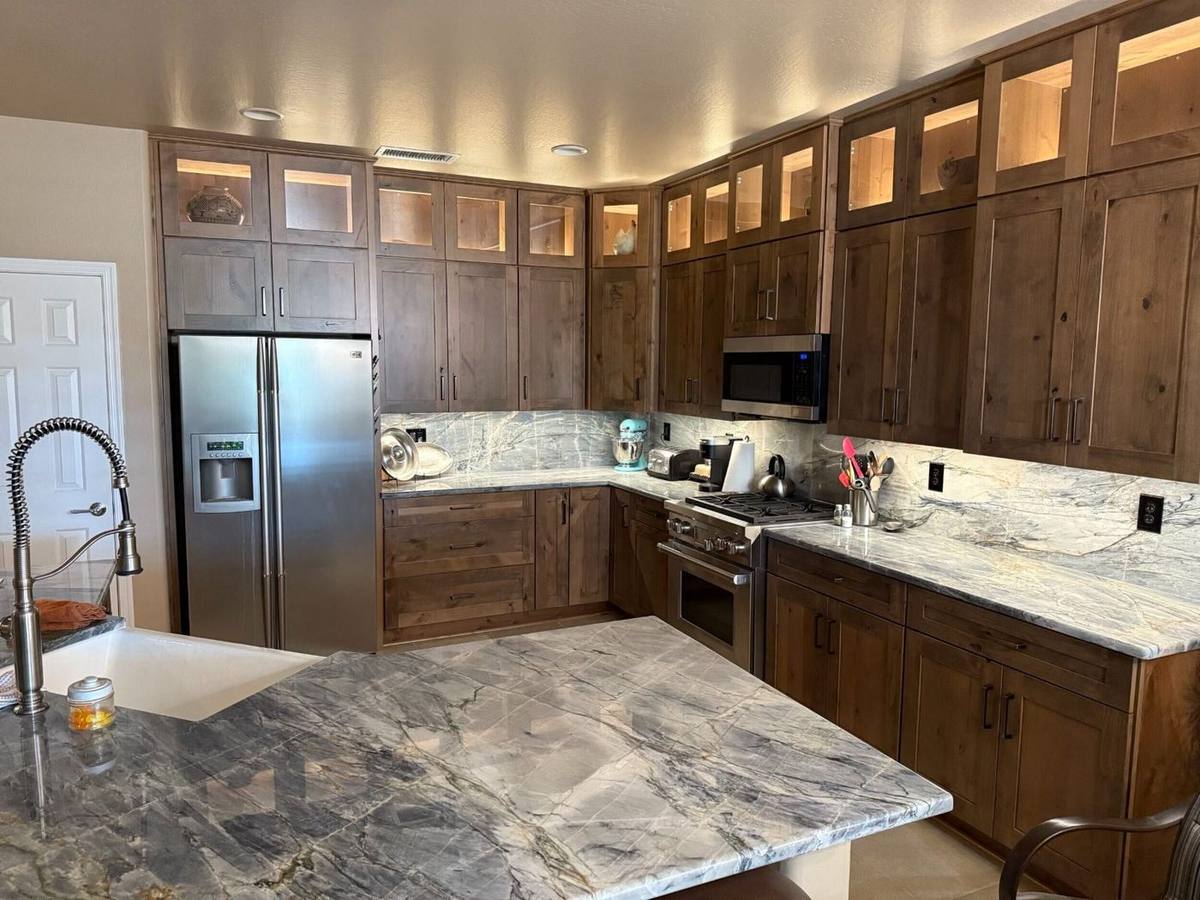 Remodeled kitchen featuring rustic wood cabinetry, under-cabinet lighting, and striking blue-gray quartzite countertops