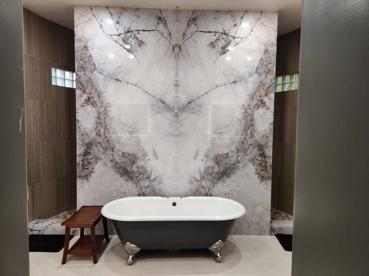 Freestanding clawfoot bathtub positioned in front of a dramatic book-matched marble accent wall